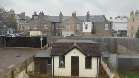 Danny Fullbrook/BBC A view out of a second floor bedroom window shows a view of the EastEnders set.