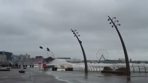 The Blackpool Lads A giant wave can be seen splashing near the Promenade, with waves splashing over the promenade too.