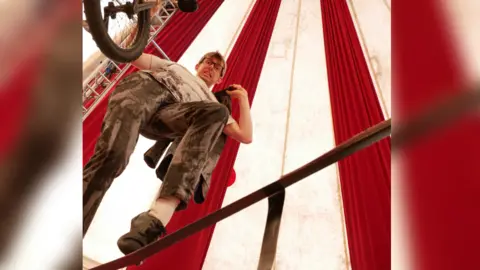 Sam Morley Sam Goodburn on top of a unicycle inside a circus tent