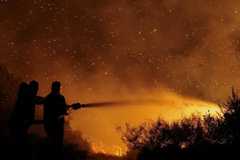 Reuters Local residents try to extinguish a wildfire burning in Keratea, near Athens, Greece. Photo: 8 August 2025