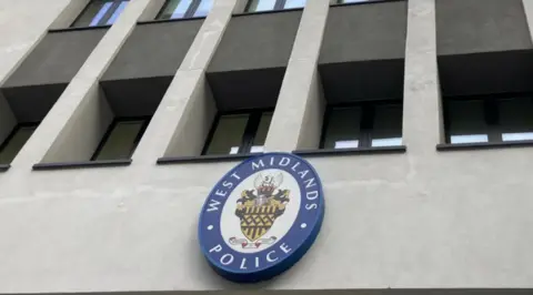 A blue West Midlands Police logo on the front of a gray wall