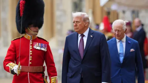 Getty Images US President Donald Trump (C) and King Charles III (R) review the Guard of Honour after the arrival at Windsor Castle on day two of the US President Donald Trump's second state visit to the UK on September 17, 2025 in Windsor, England. 
