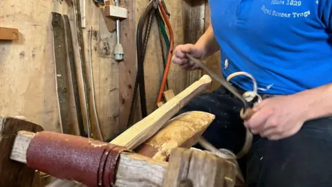 George Carden/BBC A piece of wood is shaved down with a blade to become flexible enough to bend into a handle