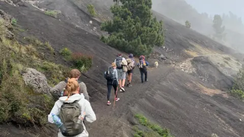 Tourists scaling the volcano connected  a tiny  way   on  the broadside  of the mountain