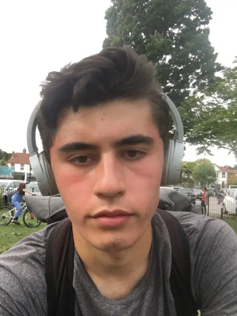 Metropolitan Police Selfie of Daniel Khalife wearing a grey t-shirt and a brace  of airy  grey headphones