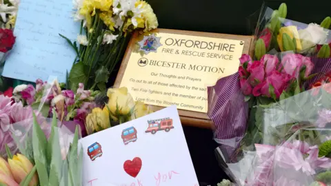 A golden plaque, flowers and handwritten cards.