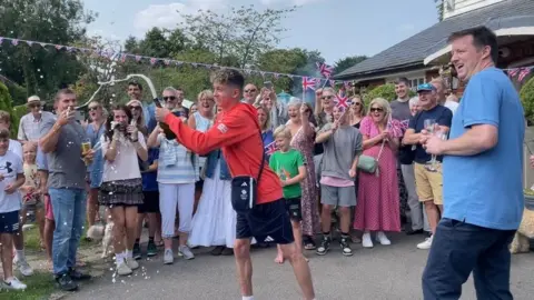 Toby Roberts arriving at celebration event in Surrey to a crowd of cheering family and friends.