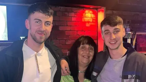 Group picture of brother Zak Slater, mother Debbie Duncan and Jay Slater smiling in a bar