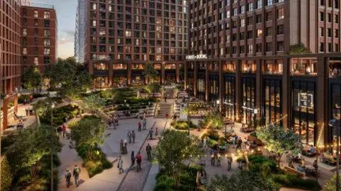 The image shows a square at dusk with trees and walkways through it leading to several building with shops on lower floors and living space above.

