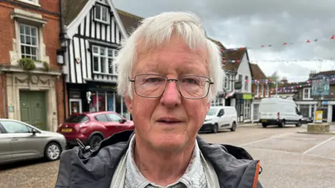 Darren Rozier/BBC A head and shoulders image of Clive Eastwood. He is standing in the middle of Framlingham. He is wearing glasses and a jacket and looking into the camera.
