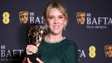 Evans with her Bafta award, wearing a green sparkly dress