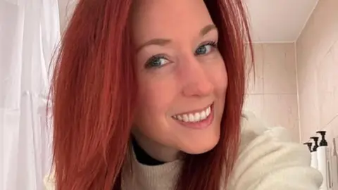 Sian Haddon Sian Haddon has long, dyed red hair. She smiles for the camera.
