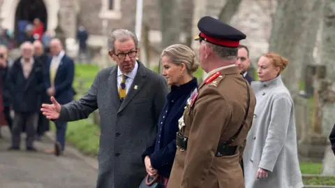BBC President of the States of Alderney William Tate talks to the Duchess of Edinburgh while walking outside a church.