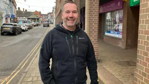 Neil Johnson standing smiling at the camera while standing in the high street.