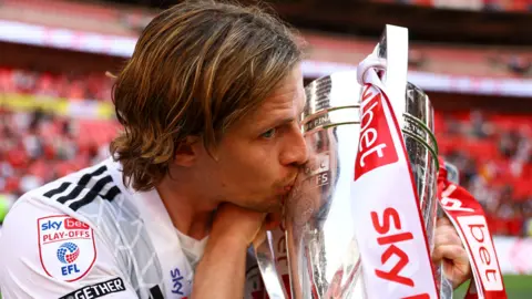 Danilo Orsi kisses the League Two play-off final trophy