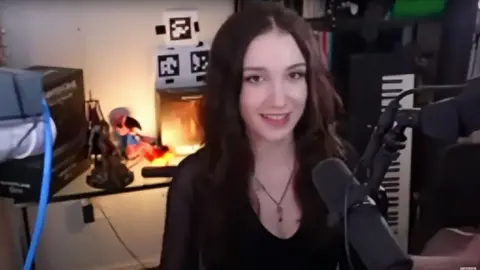 The streamer PerriKaryal sits in a room behind a microphone