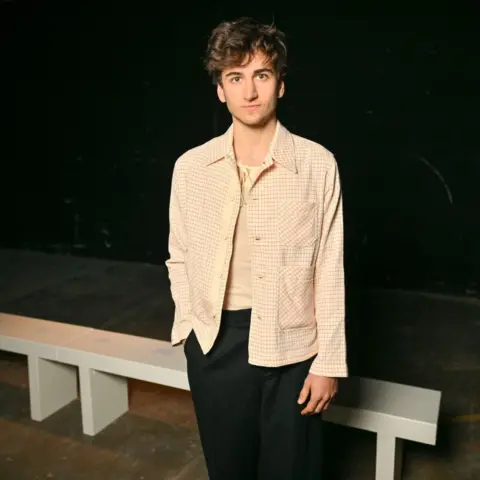 Dave Benett/Getty Images Sebastian Croft wears a patterned off-white shirt and black trousers