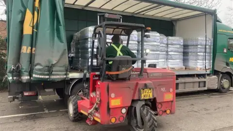 Piers Hopkirk / BBC A forklift operator moves pallets of bottled water from a lorry.