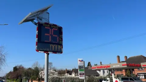 A view of a speed indicator device flashing 35mph and warning the driver to slow down.