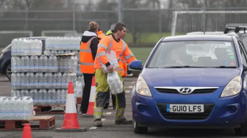 EDDIE MITCHELL South East Water workers in hi vis hand out bottled water to drivers at East Grinstead Rugby Club.
