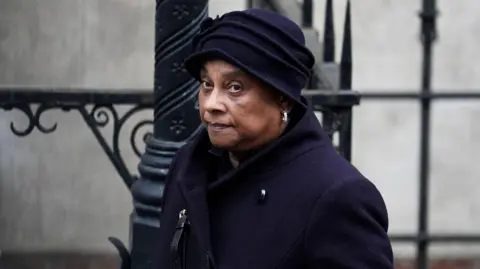 PA Media Mid-shot of Baroness Doreen Lawrence wearing a black coat and black hat looking off-camera.