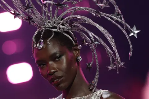 ANGELA WEISS / AFP / GETTY IMAGES A woman wears a silver, multi-pronged headdress which trails large stars.
