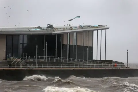 Getty Images A swimming pool building next to the coast. Part of the roof has blown off due to high winds