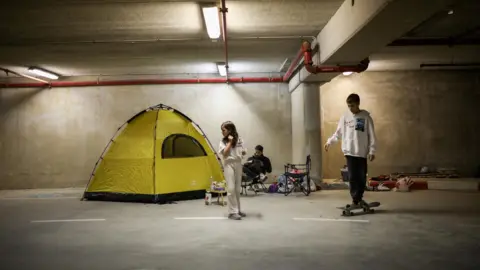 Reuters An Israeli family shelter in an underground car park in Haifa, northern Israel (1 March 2026)
