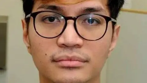 Reynhard Sinaga, a young man with black spectacles, staring into the camera.