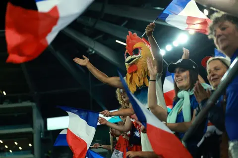 Getty Images A man wearing a rooster head joins the crowd cheering for France