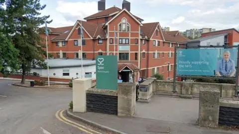 The entrance to the Spire Hospital is pictured from the road. Redbrick hospital buildings are seen in the background