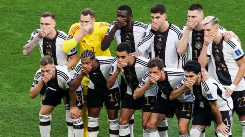 Germany's players protest by covering their mouths before their 2022 World Cup game against Japan in Qatar