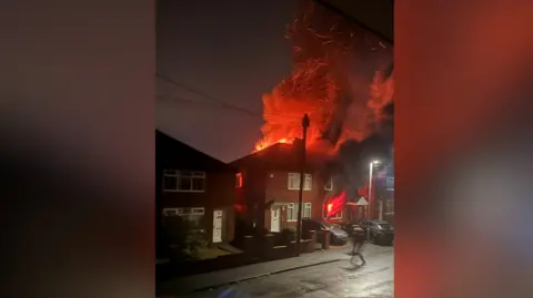 Jodie Shovelton Billowing smoke and flames as the fire burned at the house. Large orange cloud of smoke rises high into the dark sky.