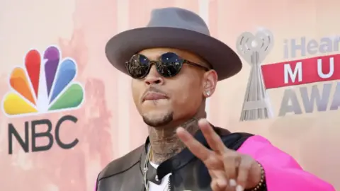 Chris Brown wearing a hat and shades at a showbiz event