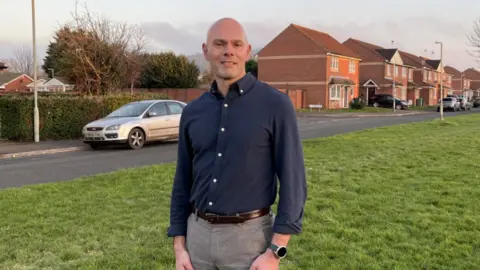 A photo of Guy Stenson, Chief Executive of Gloucester City Homes, stood in front of a house in Podsmead, Gloucester