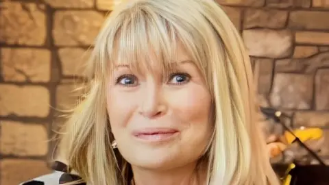 A woman with long blonde hair smiling at the camera