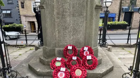 Nigel Gourlay Grey stone memorial with engraved names of veterans and poppy wreaths laid at the bottom