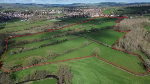 nineteen47 Images of a fields with a red line around it which shows where the housing will go if approved.