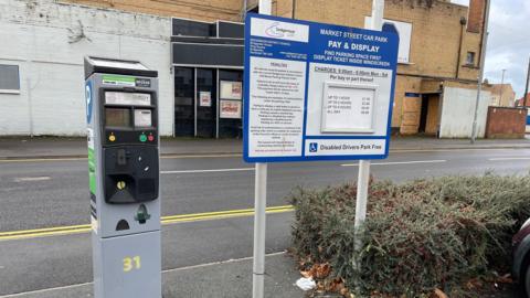 A parking meter with a pricing sign next to it