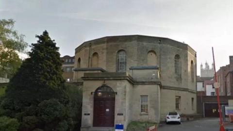 A streetview picture of Gloucester Crown Court. The building is an unusual round shape, with a flat roof and large windows. 