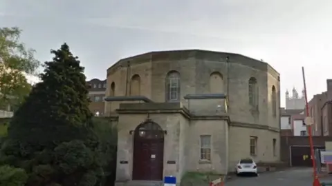 Google A streetview picture of Gloucester Crown Court. The building is an unusual round shape, with a flat roof and large windows. 