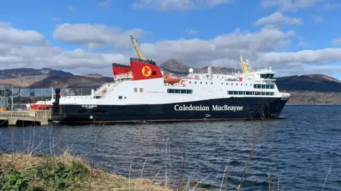 The Glen Sannox moored in slightly choppy water at Brodick under a cloudy blue sky