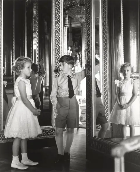 Lord Snowdon Princess Anne and King Charles as young children, standing beside a mirror in Buckingham Palace