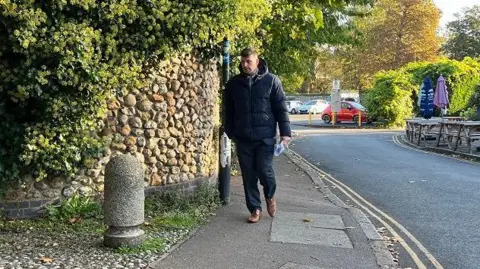 Stuart Worby arriving at Norwich Crown Court wearing brown shoes, black trousers and a black puffer jacket. 