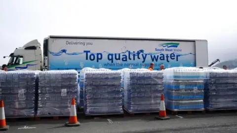 A South West Water lorry parked behind pallets of bottled water.