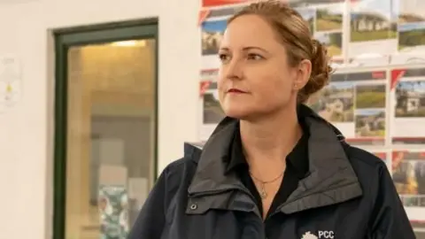 Alison Hernandez with her brunette hair tied back and wearing a black jacket with a PCC logo