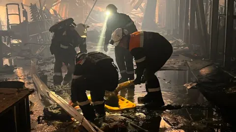 Ukrainian emergerncies workers search through the rubble at a shopping centre in Kryvyi Rih following a deadly Russian drone attack. Photo: 22 August 2026