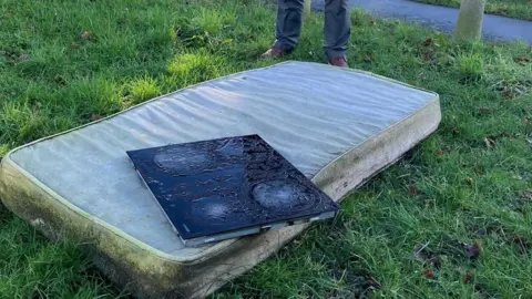 A dirty mattress dumped on grass