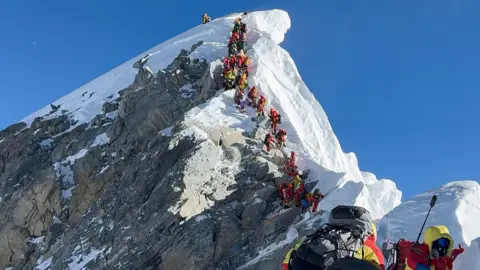 Getty Images A line of climbers walking up to the summit of Mount Everest. 