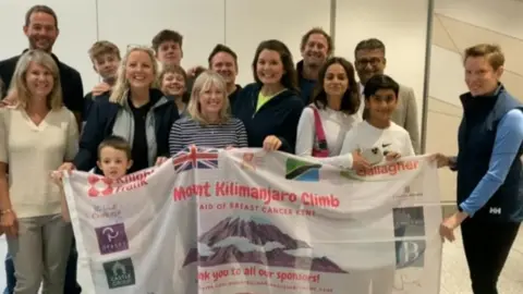 Tracey Crouch holding a banner with a group at Gatwick Airport